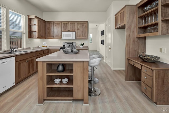 kitchen featuring light wood-style flooring, open shelves, a sink, a kitchen breakfast bar, and white appliances