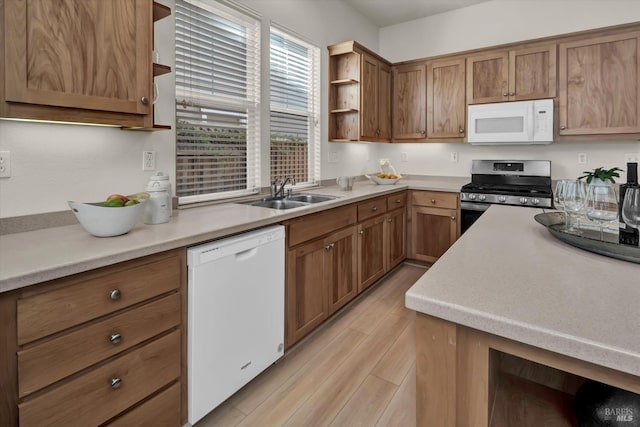 kitchen featuring brown cabinets, light wood-style flooring, open shelves, a sink, and white appliances