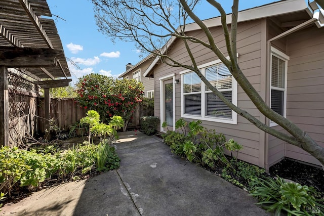 view of property exterior featuring a patio, a pergola, and fence