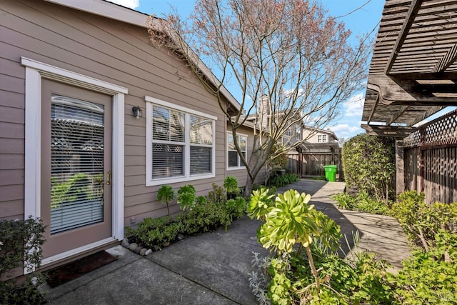 property entrance featuring a patio area, a pergola, and fence