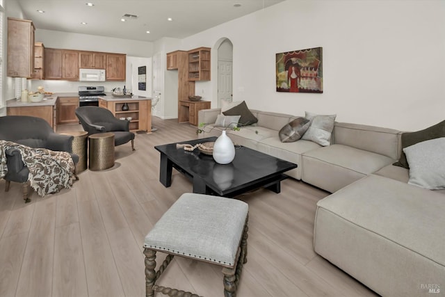 living area featuring recessed lighting, light wood-type flooring, and arched walkways