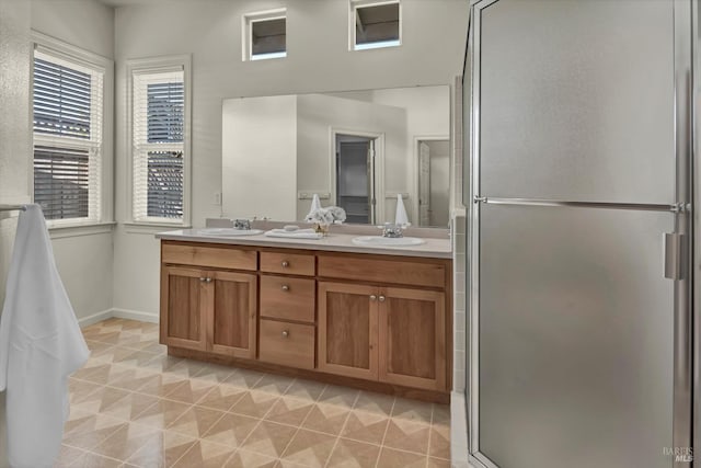 bathroom featuring tile patterned flooring, a shower stall, double vanity, and a sink