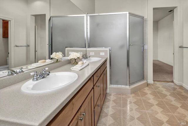 bathroom featuring tile patterned flooring, a stall shower, double vanity, and a sink