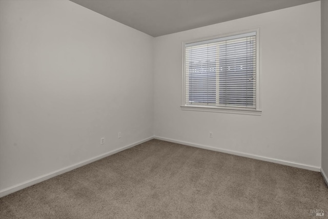 carpeted empty room featuring baseboards