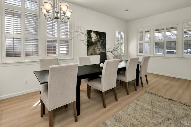 dining space featuring an inviting chandelier, light wood-style flooring, and baseboards