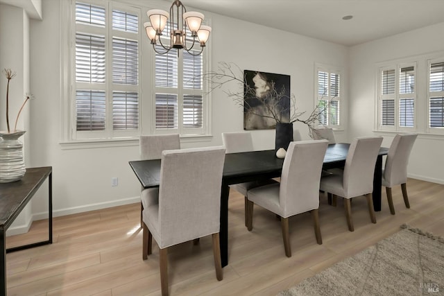 dining area featuring an inviting chandelier, light wood-style flooring, and baseboards