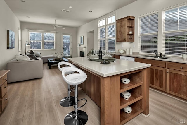 kitchen with visible vents, open shelves, ceiling fan, a sink, and a center island