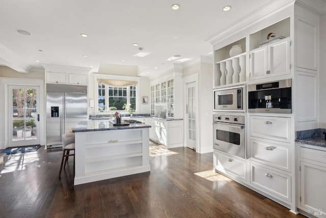 kitchen featuring built in appliances, white cabinetry, a center island, and open shelves