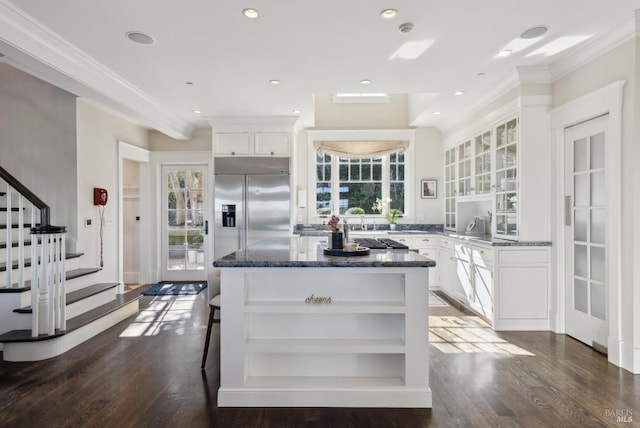 kitchen featuring open shelves, ornamental molding, dark stone countertops, and a kitchen island