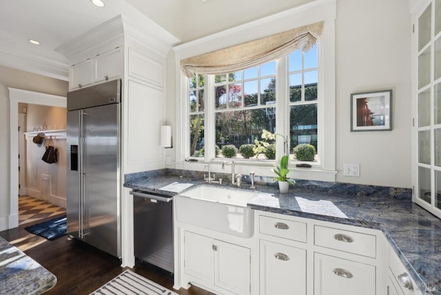 kitchen featuring dark stone counters, recessed lighting, a sink, stainless steel appliances, and white cabinets