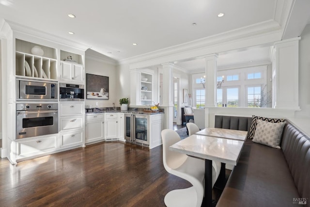 dining room featuring crown molding, wine cooler, dark wood-style floors, and ornate columns