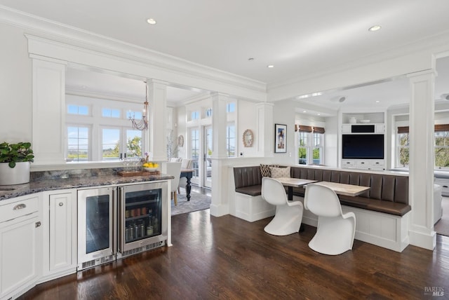 interior space featuring ornate columns, dark wood-type flooring, breakfast area, and ornamental molding