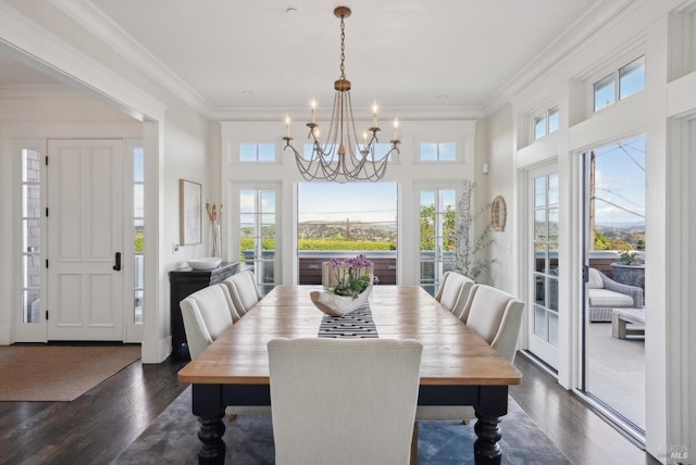 dining space with dark wood-type flooring, a chandelier, and ornamental molding