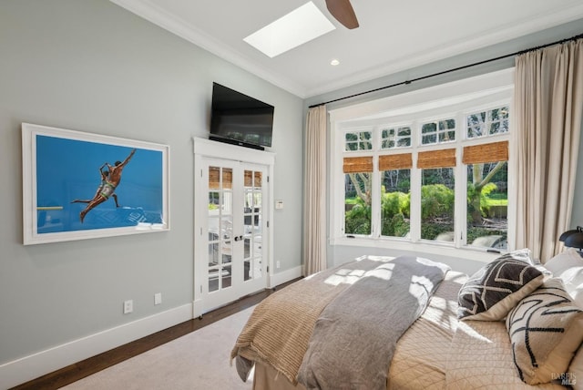 bedroom featuring wood finished floors, baseboards, a skylight, and crown molding