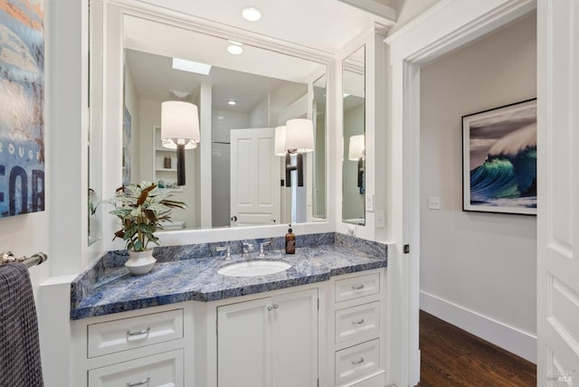 bathroom with vanity, wood finished floors, and baseboards