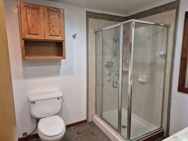 bathroom featuring baseboards, toilet, a shower stall, and tile patterned flooring