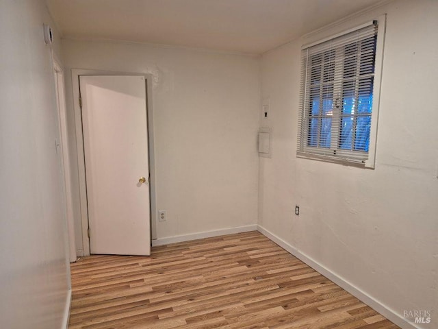 spare room with baseboards and light wood finished floors