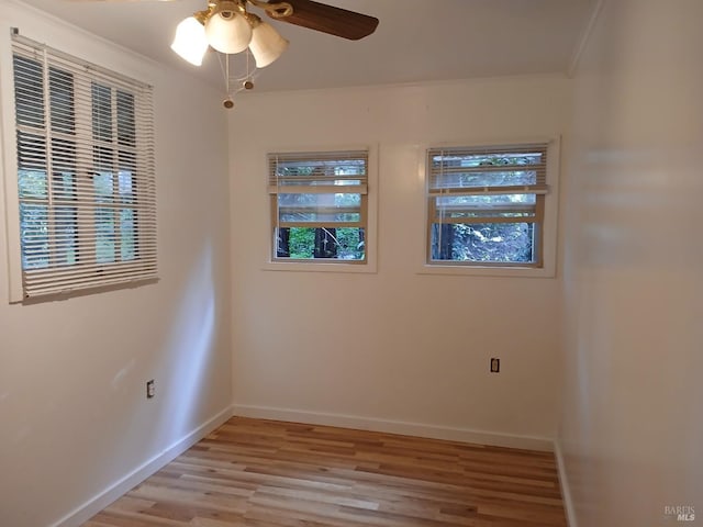 unfurnished room with crown molding, light wood-style floors, baseboards, and ceiling fan