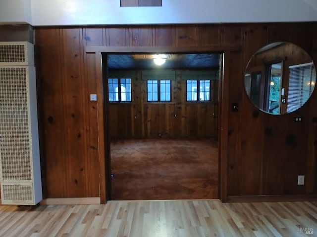 entrance foyer featuring wood walls, a heating unit, and wood finished floors