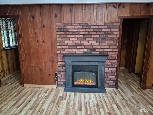 room details featuring wooden walls, wood finished floors, and a fireplace