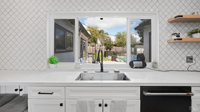 kitchen featuring light stone counters, open shelves, a sink, black dishwasher, and white cabinetry