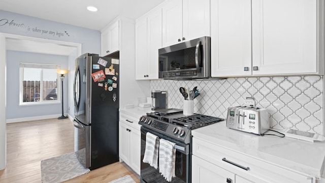 kitchen with light stone countertops, backsplash, appliances with stainless steel finishes, and white cabinetry