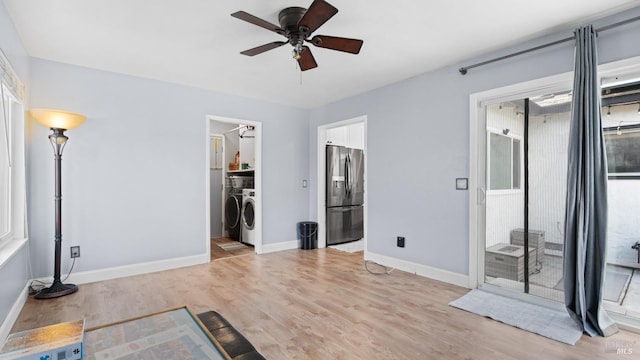 interior space with a walk in closet, independent washer and dryer, light wood-style flooring, access to outside, and stainless steel fridge