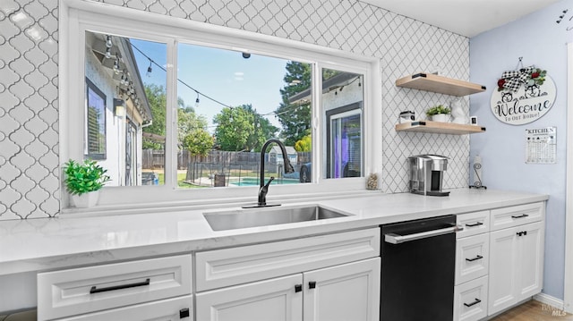 kitchen featuring open shelves, a sink, plenty of natural light, dishwasher, and white cabinets