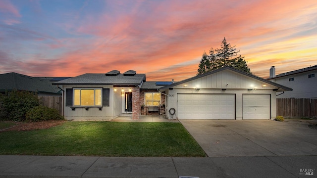 view of front of house with fence, concrete driveway, a front yard, roof mounted solar panels, and a garage