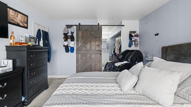 bedroom with a barn door, a closet, carpet, baseboards, and a spacious closet