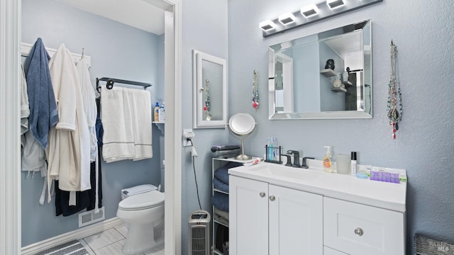 bathroom featuring vanity, toilet, and visible vents