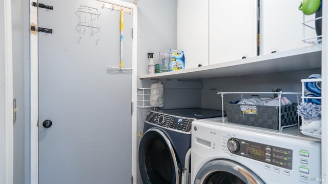 clothes washing area featuring washer and dryer and cabinet space