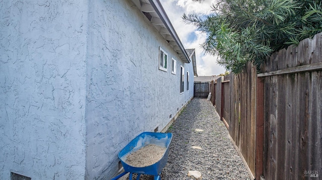 view of side of property featuring crawl space, a fenced backyard, and stucco siding