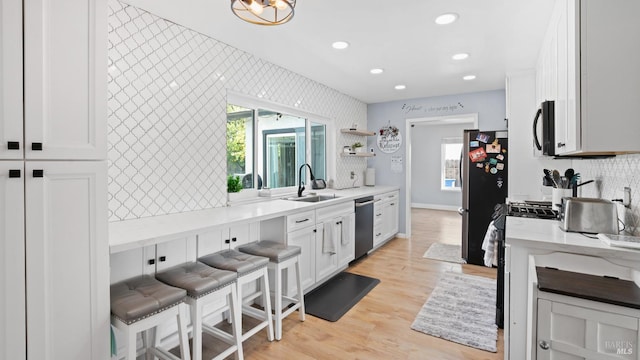 kitchen featuring white cabinetry, light wood-type flooring, appliances with stainless steel finishes, and a sink