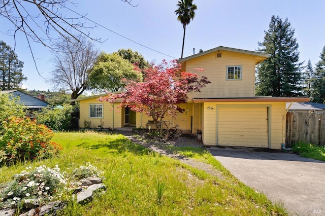 traditional-style home with an attached garage, fence, and aphalt driveway
