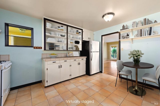 kitchen featuring white cabinetry, open shelves, gas range gas stove, and freestanding refrigerator