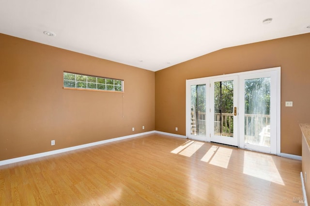 unfurnished room featuring light wood finished floors, baseboards, and lofted ceiling