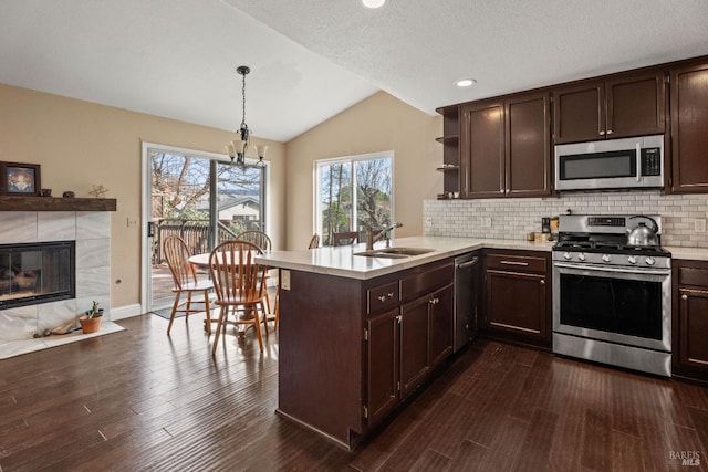 kitchen featuring a peninsula, open shelves, a sink, stainless steel appliances, and light countertops