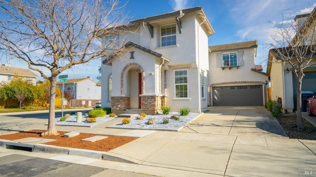 mediterranean / spanish house featuring stone siding, stucco siding, concrete driveway, and a garage