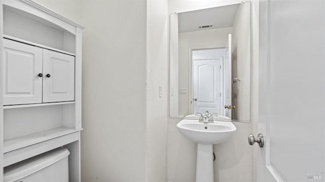 bathroom featuring toilet, visible vents, and a sink