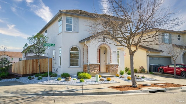 mediterranean / spanish-style house featuring fence, stucco siding, a garage, stone siding, and driveway