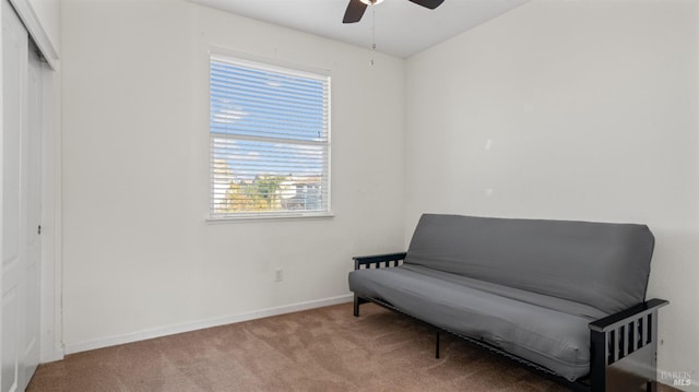 living area featuring baseboards, a ceiling fan, and carpet