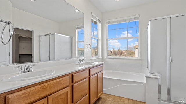 full bath with double vanity, a stall shower, a bath, and a sink