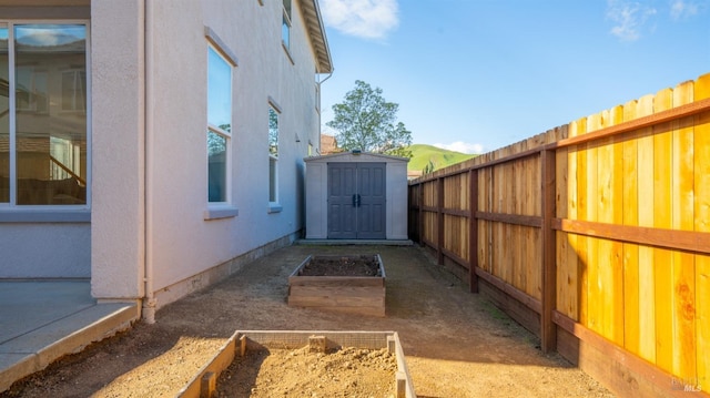 exterior space featuring a garden, a fenced backyard, stucco siding, an outdoor structure, and a storage shed