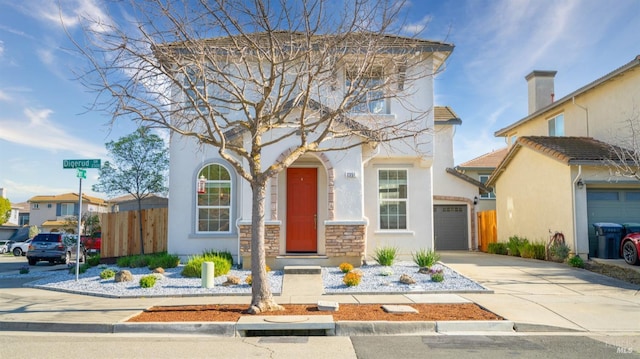 view of front of home featuring stucco siding, a garage, concrete driveway, and fence