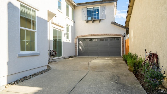 view of side of property featuring stucco siding, driveway, and a garage