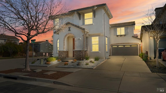 mediterranean / spanish-style house with stone siding, stucco siding, driveway, and a garage