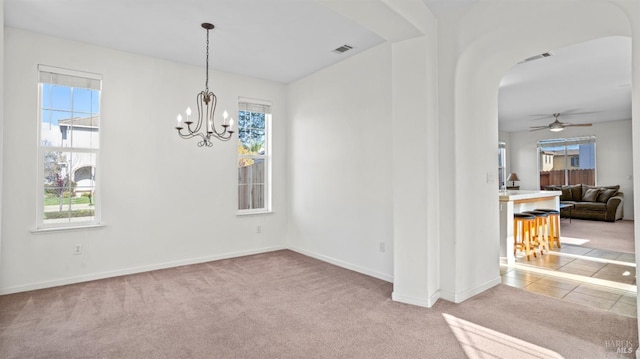 tiled spare room with arched walkways, carpet flooring, ceiling fan with notable chandelier, and visible vents