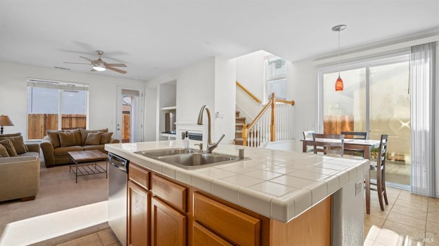 kitchen with tile counters, open floor plan, dishwasher, a ceiling fan, and a sink