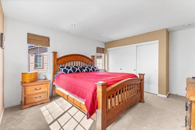 bedroom with recessed lighting, baseboards, a closet, and light carpet